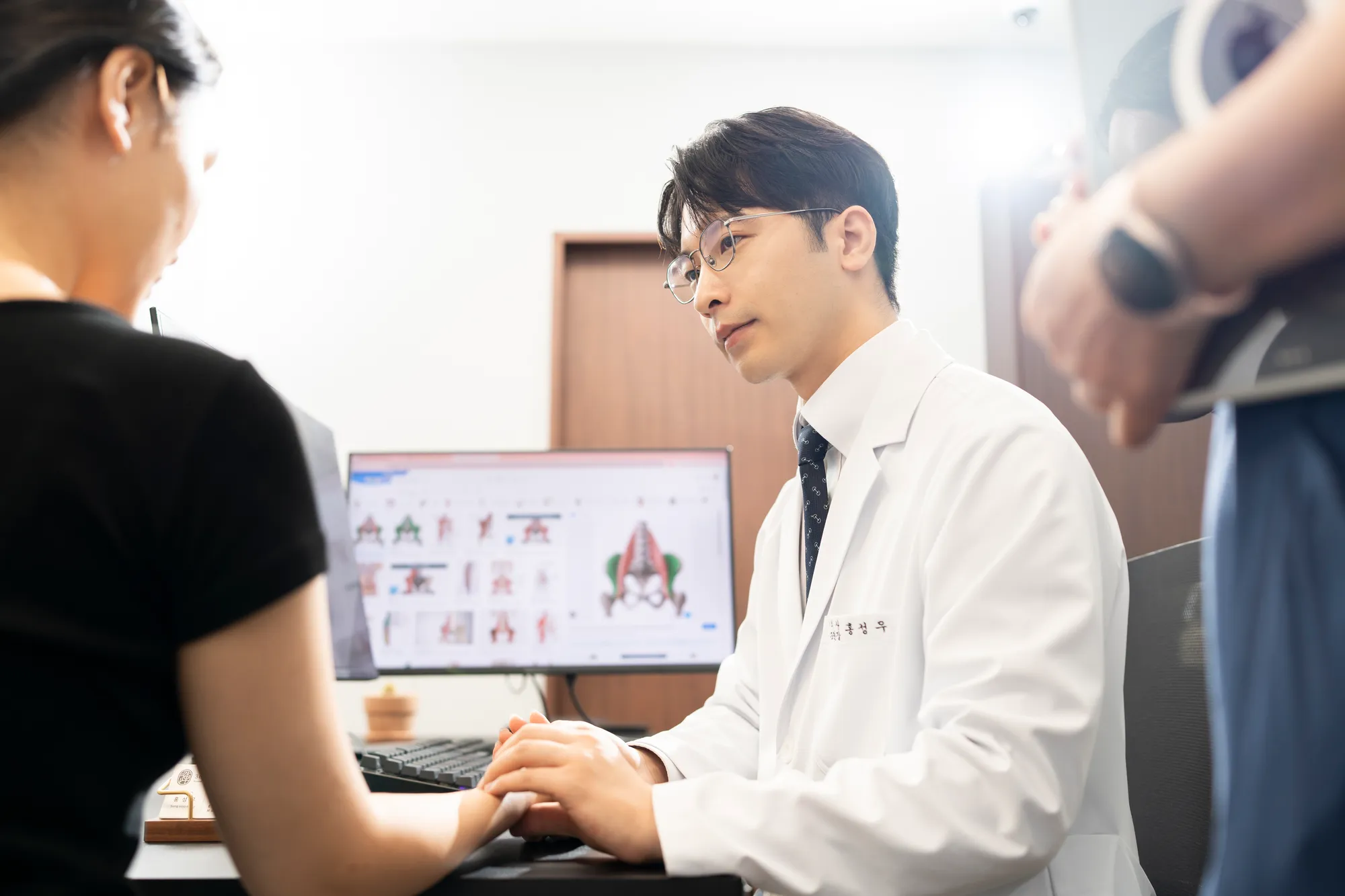 홍성우 대표원장이 환자의 손목을 촉진하며 상담하는 모습